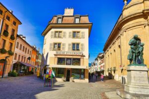 Buildings lining a cobblestone street with a statue.